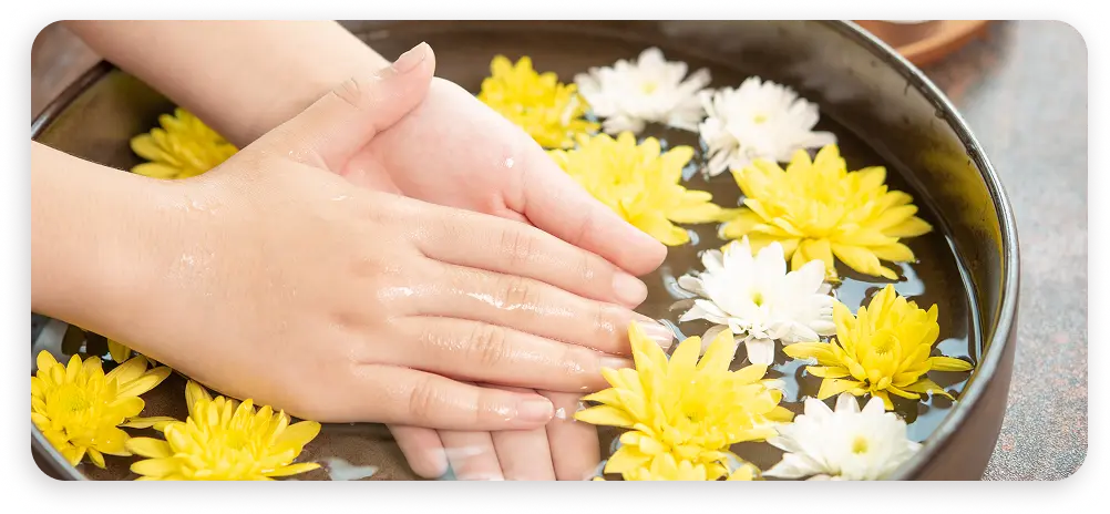 Suda yüzen sarı ve beyaz çiçeklerle rahatlatıcı el spa tedavisi, sakin bir wellness atmosferi yaratıyor.